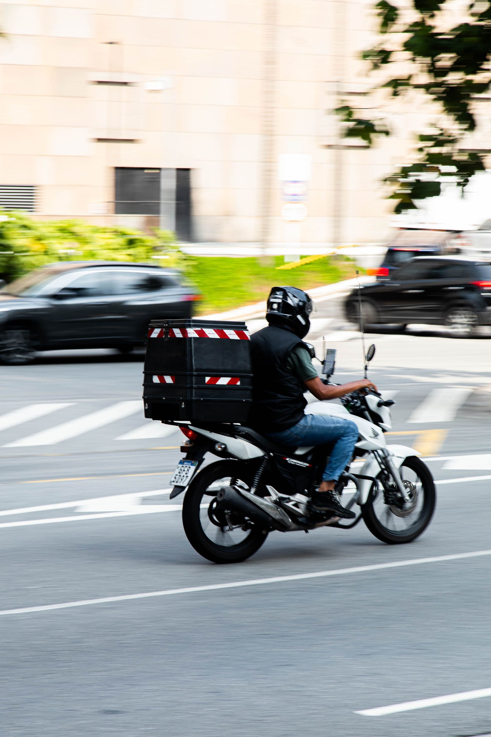 Un chauffeur ZELLA à moto transportant un colis en ville